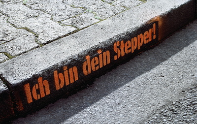 Auf einem Bordstein ist aufgesprüht Ich bin dein Stepper