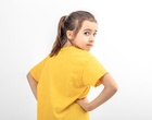 Ein Mädchen in gelbem T-Shirt steht mit dem Rücken zum Betrachter.