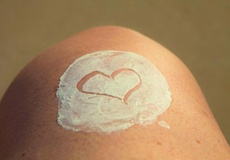 Haut mit Creme, in die ein Herz gemalt ist.