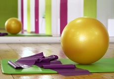 Auf einer Gymnastikmatte liegen ein großer Ball und ein Strechband.