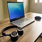 Auf einem Schreibtisch liegen ein Laptop und Kopfhörer.