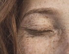 Ausschnitt eines Gesichts einer rothaarigen Frau mit Sommersprossen.