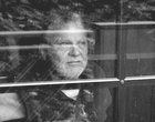 Ein bärtiger älterer Mann schaut aus dem Fenster. Symbolbild für Depression.