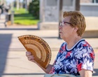 Eine Frau fächelt sich mit einem Fächer Luft zu.