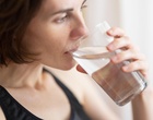 Eine Frau trinkt ein Glas Wasser.