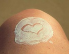 Haut mit Creme, in die ein Herz gemalt ist.
