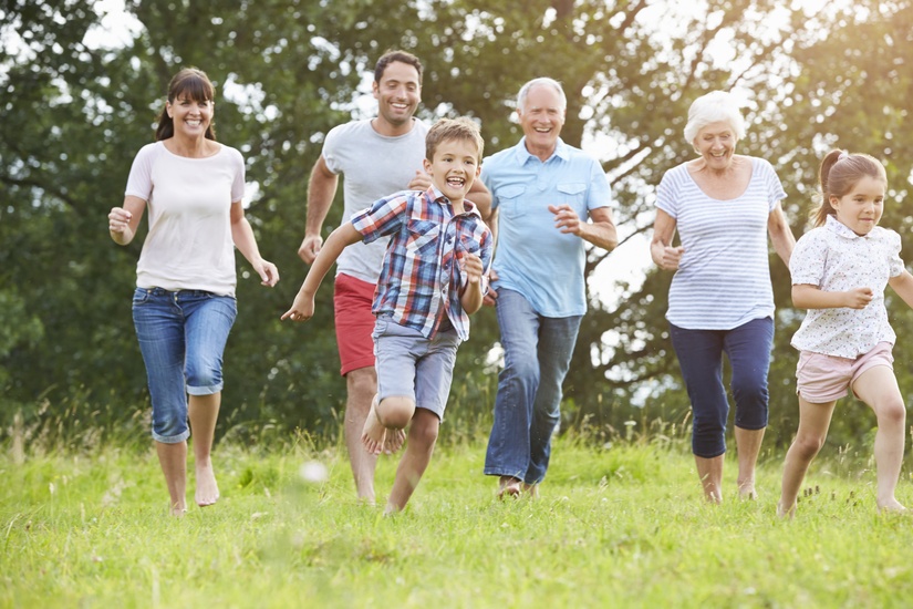 Eine Mehr-Generationenfamilie rennt über eine Wiese.