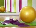 Auf einer Gymnastikmatte liegen ein großer Ball und ein Strechband.