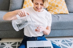 Eine Frau gießt sich ein Glas Wasser ein.