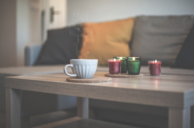 Eine Tasse Kaffee und mehrere Kerzen stehen auf einem Couchtisch.