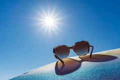 Sonnenbrille in Großaufnahme vor einem strahlenden Himmel.