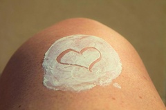 Haut mit Creme, in die ein Herz gemalt ist.