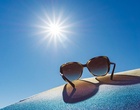 Sonnenbrille in Großaufnahme vor einem strahlenden Himmel.